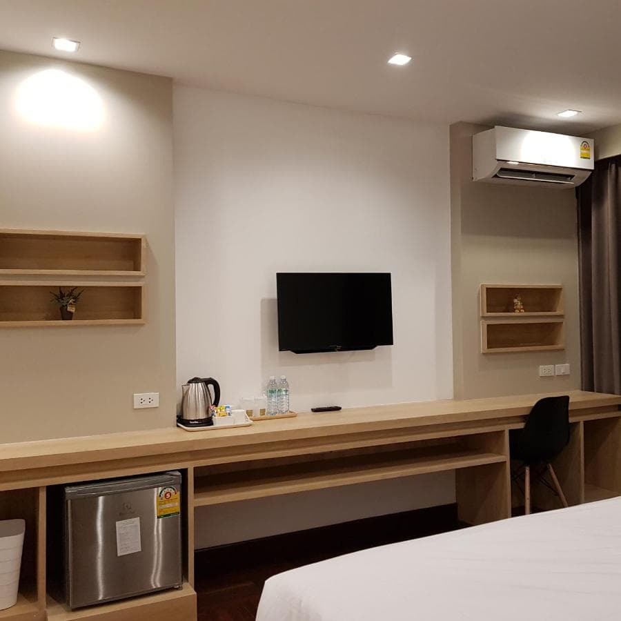 A guest room work area with a wall-mounted television, kettle and air conditioner.