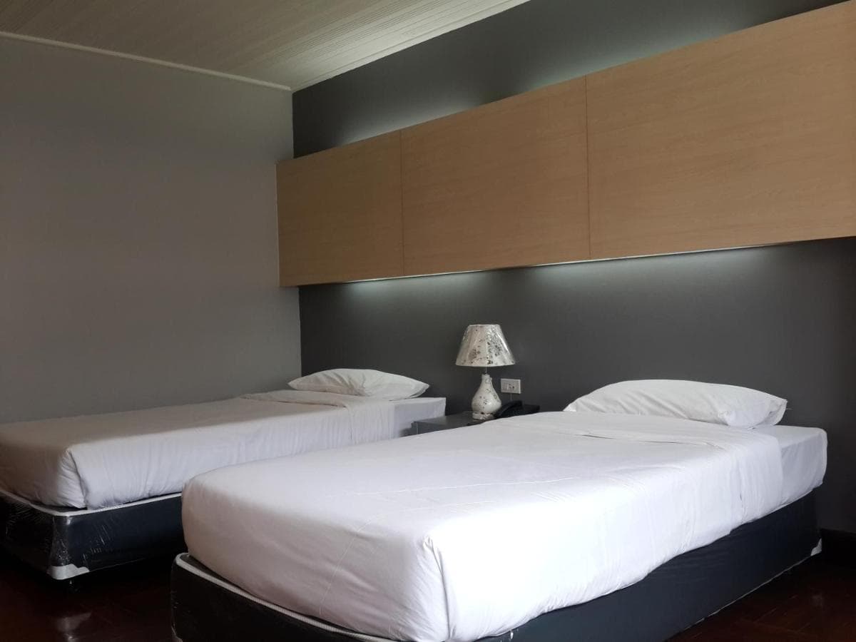 A twin room with two beds set against a dark wood headboard panel.