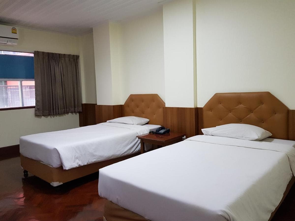A twin room with two beds against padded headboards beside a curtained window.