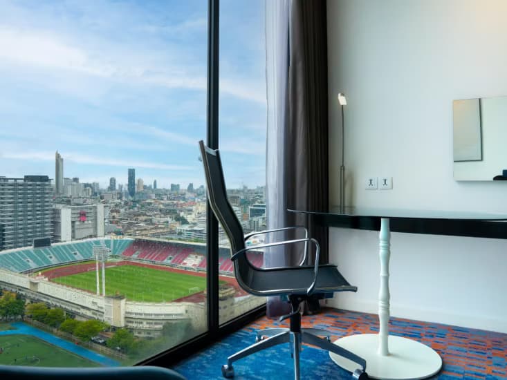 A desk beside a floor-to-ceiling window overlooking the National Stadium.