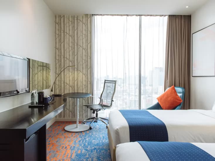 A twin room with a desk, television and a view across the rooftops.