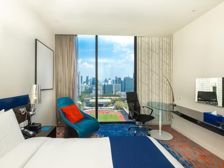 A guest room with a blue armchair and a desk facing the stadium below.