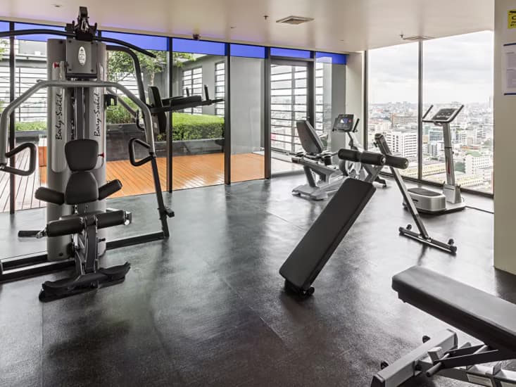 The rooftop fitness centre, with weights machines against a wall of windows.