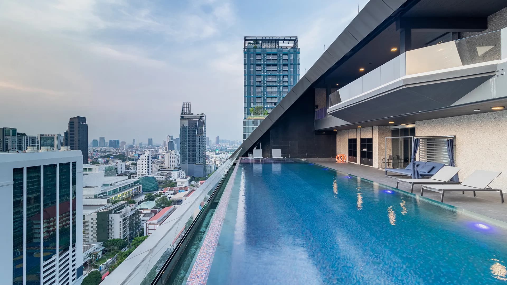 The rooftop pool running along the edge of the building above the Bangkok skyline.