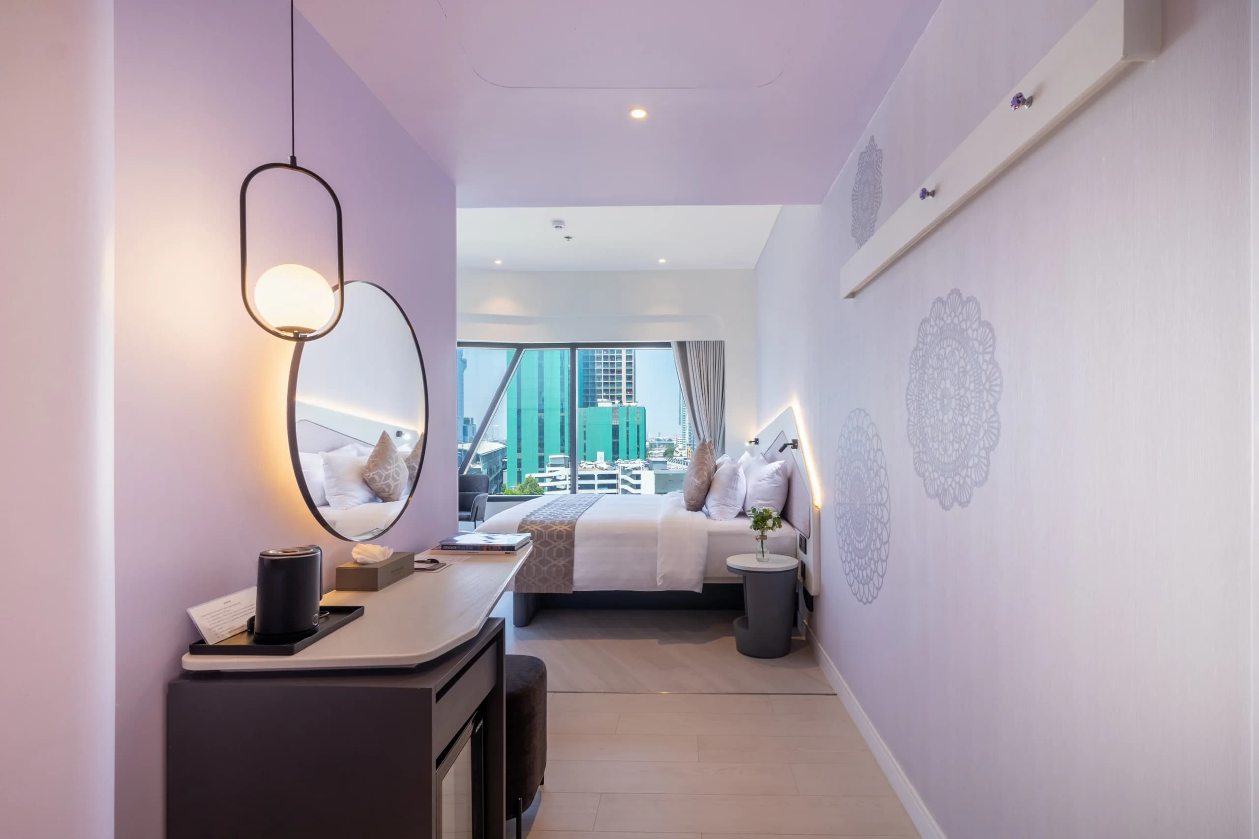 A guest room with a pendant light, dressing table and twin beds.