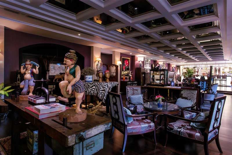 A bar and lounge furnished with dark wood, art deco panelling and sculptures.