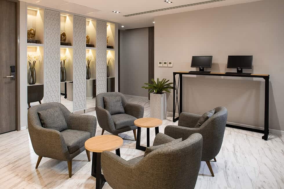 A lounge area with grey armchairs and a row of guest computer terminals.