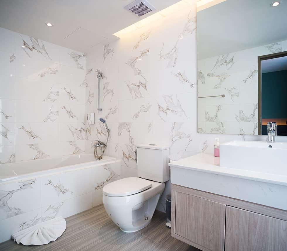 A marble bathroom with a full-size bathtub and a vanity unit.